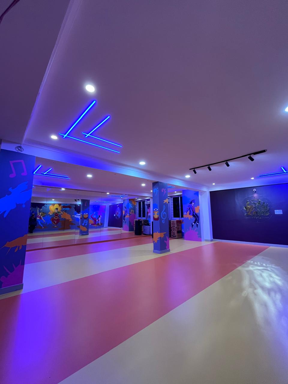 Dual-tone flooring, emblem wall, and practice space at Laya Arts Studio